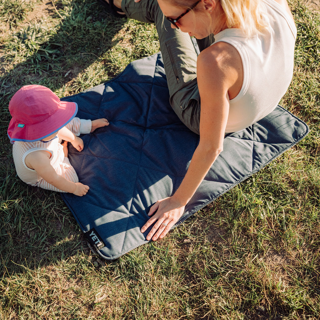 Mum and baby sitting on a YETI small lowlands blanket.