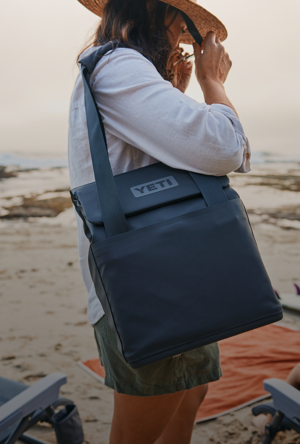 Person on a beach holding a YETI cooler bag