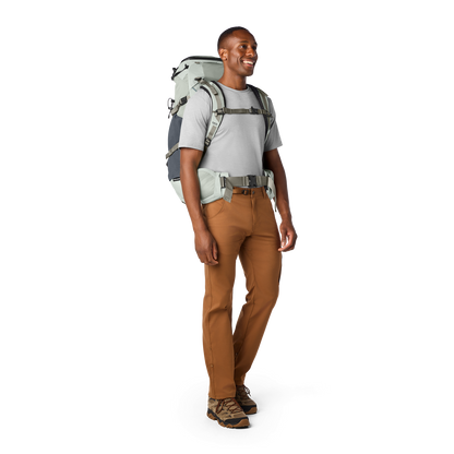 Man wearing a hiking backpack and brown trousers on a white background