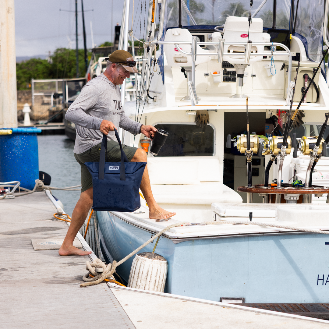 Man standing on a dock next to a boat  with fishing equipment.